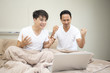 © Jestercine - Man and friend watching porn movie with laptop in bedroom together.