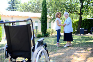 Wall Mural - cheerful mature woman visiting her mother elderly senior female walk in retirement house hospital garden