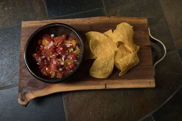 Homemade salsa and chips in soft light from above