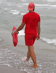 Wall Mural - Lifeguard with red uniform controls bathers