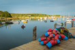 Lobster buoys in a large pile on the dock overlook the harbor