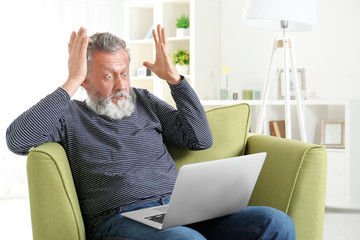 Sticker - Handsome elderly man sitting in armchair with laptop