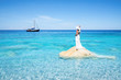 Elegante Frau in weißen Abendkleid steht träumend auf einen Felsen im Mittelmeer
