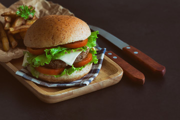 Homemade hamburger on plaid napkin with french fries. Delicious sandwich hamburger with meat or pork ham cheese and fresh vegetable. Hamburger or sandwich is the popular fast food for brunch or lunch.