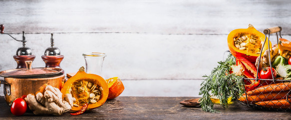 Sticker - Autumn seasonal  cooking concept. Various autumn seasonal organic vegetables: pumpkin,carrot,paprika,tomatoes,ginger in basket on wooden kitchen desk tables with pot at wall background, front view.