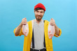 © wayhome.studio  - Positive fisherman with appealing smile having attractive blue eyes, dark beard with mustache wearing red hat and yellow raincoat holding two fish in hands being glad to catch them yesterday