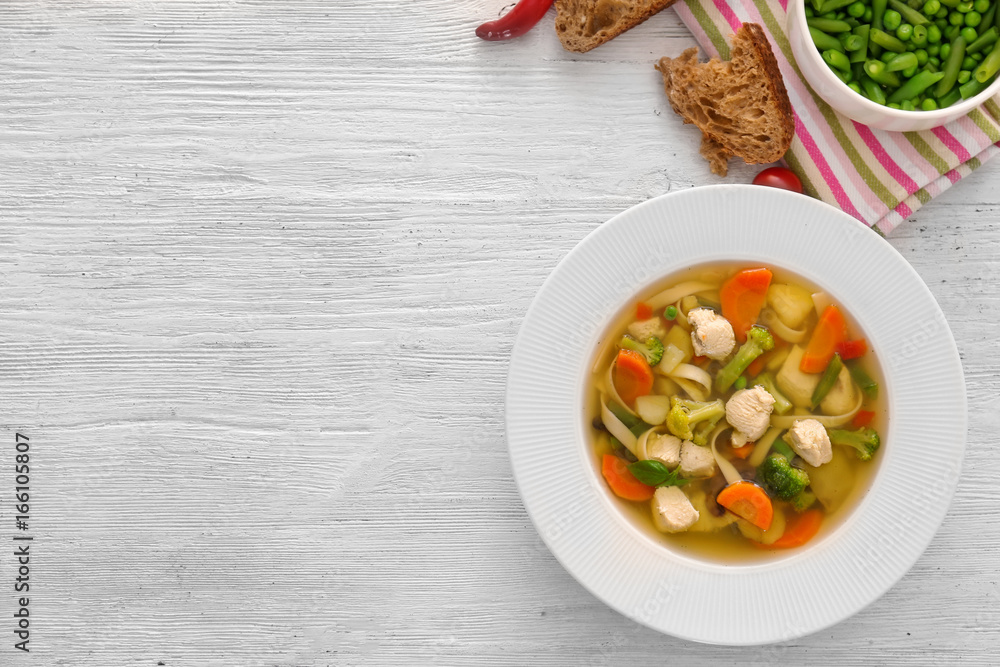 Plate with delicious turkey soup on wooden background