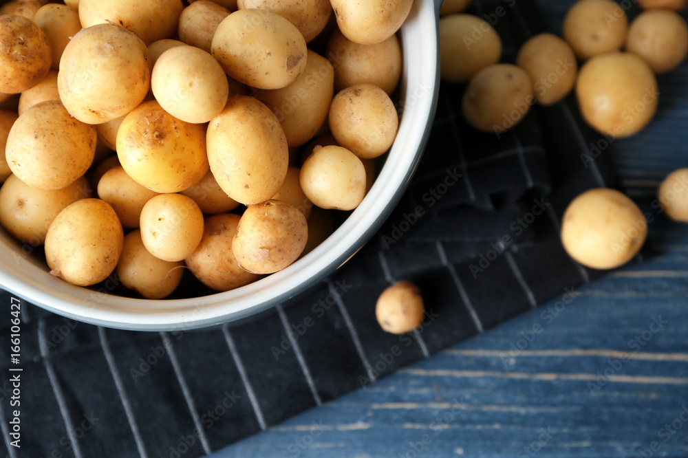 Casserole with raw organic potato on wooden table