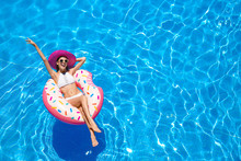 Beautiful Young Woman With Inflatable Donut In Blue Swimming Pool