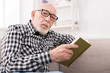 © Prostock-studio - Senior man reading book at home, copy space