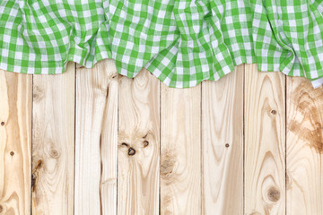 Wall Mural - Green checkered tablecloth on wooden table, top view