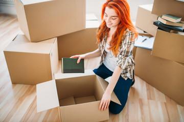 Woman unpacking cardboard boxes in new home