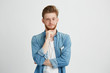 © Cookie Studio - Portrait of confident young handsome man with beard looking at camera thinking with hand on chin over white background.