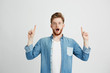 © Cookie Studio - Portrait of surprised young handsome man looking at camera with opened mouth pointing finger up over white background.