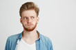 © Cookie Studio - Portrait of nervous young man with beard wearing jean shirt looking in side over white background.