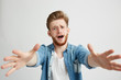 © Cookie Studio - Portrait of young handsome man with opened mouth looking stretching hands to camera over white background.