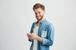 © Cookie Studio - Young cheerful guy in headphones smiling holding phone looking at camera listening to music over white background.