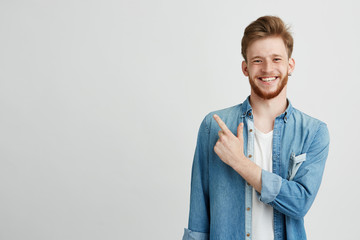 portrait of cheerful young man smiling looking at camera pointing finger up over white background.