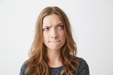 Young beautiful girl suspiciously looking in side thinking over white background.