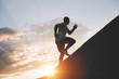 Male runner trains in an ascent to a mountain. Athlete runs through the mountains and hills at sunset