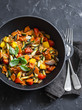 Quick ratatouille in a cast iron skillet on a dark background, top view. Steamed vegetables - vegetarian food concept