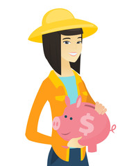 Canvas Print - Young asian farmer holding a piggy bank.