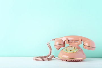 Pink retro telephone on white wooden table