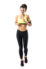 Wall Mural - Stopped motion front view of focused female jogger jogging with earbuds and phone pouch. Full body length portrait isolated on white background.