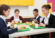 © Africa Studio - Children sitting at table in school cafeteria while eating lunch