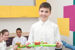 © Africa Studio - Cute boy holding tray with delicious food in school canteen