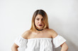 © shurkin_son - Amazing young female with long colored hair and facial piercing wearing burgundy lipstick while modeling in studio. Stunning girl in choker and white dress without shoulder-straps posing indoors