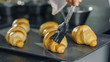 © Gorodenkoff - Professional French Baker Butters Croissants.