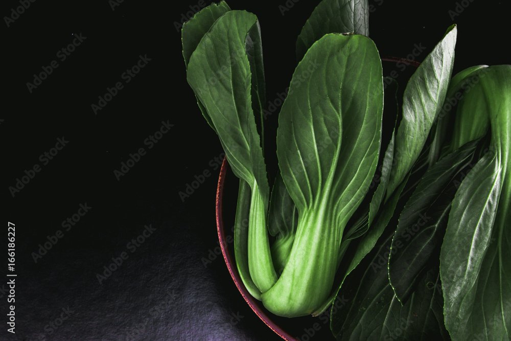 close up Fresh baby green bok choy in bowl on the  black background , overhead or top view shot - obrazy, fototapety, plakaty 