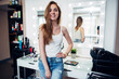 © undrey - Portrait of young smiling female model with long fair hair wearing casual clothes standing in make-up studio against makeup table and mirrors