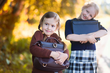 Two little girls ready back to school closeup, autumn day