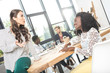 © LIGHTFIELD STUDIOS - multiethnic smiling businesswomen having conversation at workplace in office