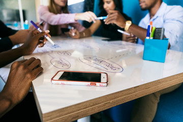 Canvas Print - Workspace: Cell Phone Sits On Table As Group Brainstorms