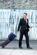 © mimagephotos - Portrait of happy business man walking with luggage and mobile phone