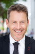 © mimagephotos - Close up smiling businessman standing outside in suit and tie