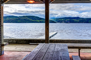 Wall Mural - Empty pier dock harbor marina in L'Anse-Saint-Jean, Canada in Quebec village with Saguenay fjord river and covered picnic area