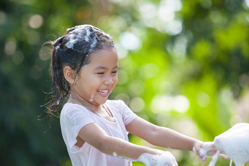 Wall Mural - Happy asian child girl having fun to bath and play with foam in outside