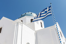 Traditional Greek Christian Church In Santorini With A Blue White Greek Flag