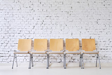 Row Of Five Empty Modern Chairs In Front Of Stylish Brick Wall