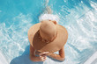 Woman in beach hat enjoying in swimming pool on Tropical Resort. Exotic Paradise. Travel, Tourism and Vacations Concept.