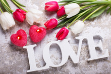 Word Love, Two Red  Candles In Form Of Heart  And  Bright Spring Flowers On  Grey Background.