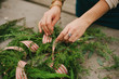 © Daring Wanderer/Stocksy - Female florist making festive holiday Christmas wreath with red striped ribbon
