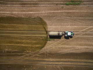 
aerial view of a tractor with a trailer fertilizes a freshly plowed agriculural field with manure in germany