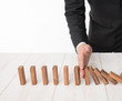 © showcake - Businessman hand trying to stop toppling dominoes on wood,stop domino effect