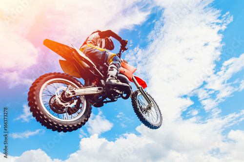 Zdjęcie XXL zawodnik na motocyklu uczestniczy w motocrossie w locie, skacze i startuje na trampolinie na tle nieba. Koncepcja aktywnego ekstremalnego odpoczynku.