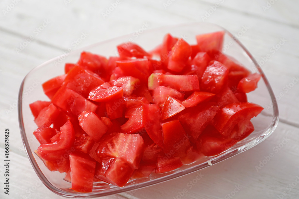 Plate with chopped tomatoes on white table, closeup
